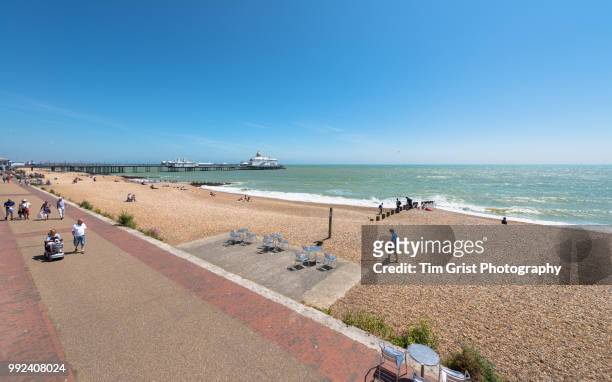 tourists on the promenade and beach at eastbourne, east sussex - eastbourne pier stockfoto's en -beelden