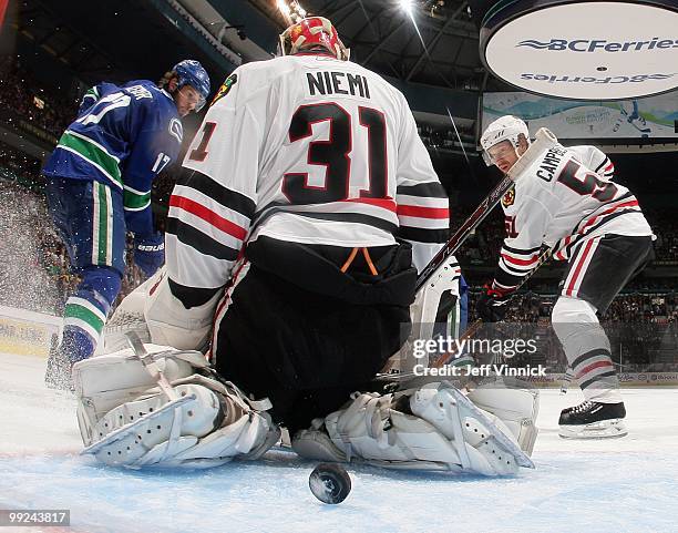 Ryan Kesler of the Vancouver Canucks and Brian Campbell of the Chicago Blackhawks look on as the puck gets between the legs of Antti Niemi of the...