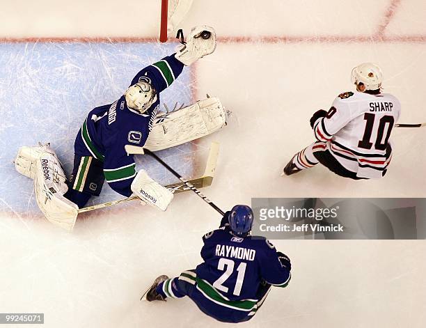 Mason Raymond of the Vancouver Canucks looks on as teammate Roberto Luongo makes a glove save off the shot of Patrick Sharp of the Chicago Blackhawks...