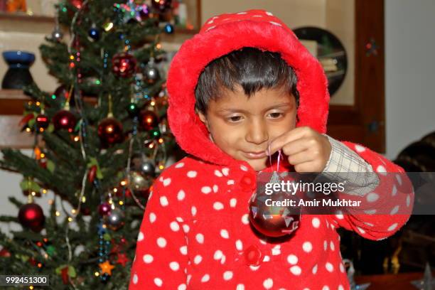 pakistani little christian girl holding bulb and decorating christmas tree on the celebration of christmas - amir mukhtar stock pictures, royalty-free photos & images