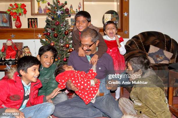 pakistani christian family (father and children) enjoying and celebrating christmas at their home - amir mukhtar stock pictures, royalty-free photos & images