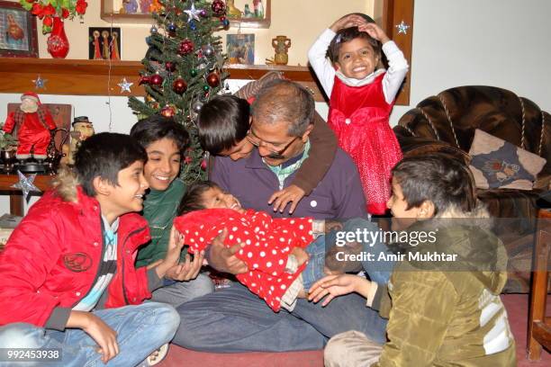 pakistani christian family (father and children) enjoying and celebrating christmas at their home - amir mukhtar stock pictures, royalty-free photos & images