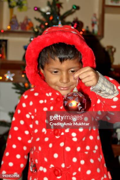 pakistani little christian girl holding bulb and decorating christmas tree on the celebration of christmas - amir mukhtar stock pictures, royalty-free photos & images