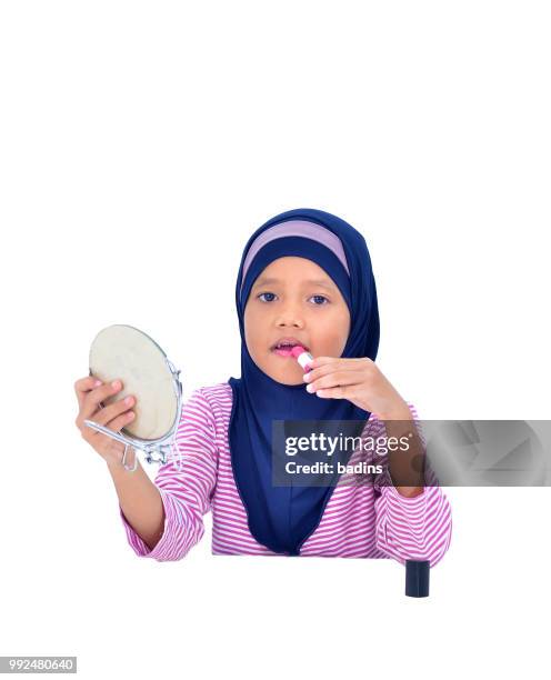 portrait of a beautiful muslim kid applying lipstick isolated on white background - white lipstick stock-fotos und bilder