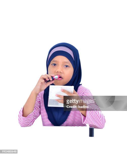 portrait of a beautiful muslim kid applying lipstick isolated on white background - white lipstick stock-fotos und bilder