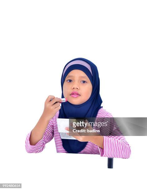 portrait of a beautiful muslim kid applying lipstick isolated on white background - white lipstick stock-fotos und bilder