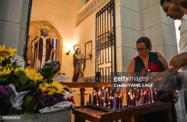 Cuban pilgrims light candles at Saint Lazarus Church in El Rincon, Havana, on July 2, 2018. - Saint Lazarus draws together Cuban interconfesional...