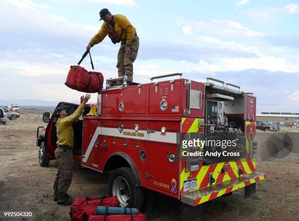 South Metro wild land firefighters Dustin Searle, left, and Wes Polk, right, unload gear after arriving back to camp at the Ft. Garland Community...