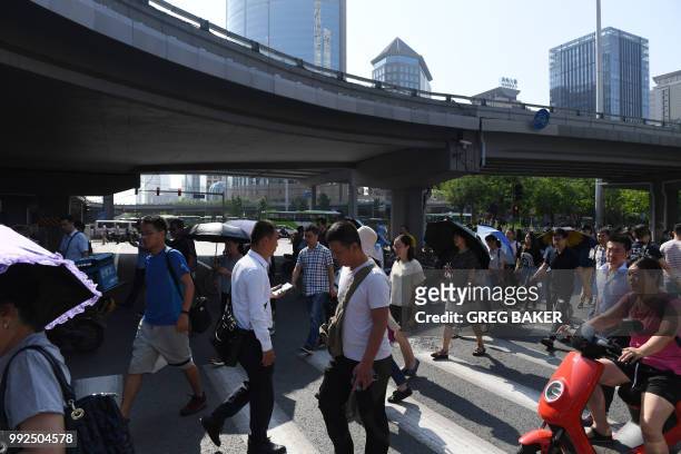 Commuters head to work in Beijing's central business district in the morning on July 6, 2018. - The US is set to begin enforcing tariffs on more than...