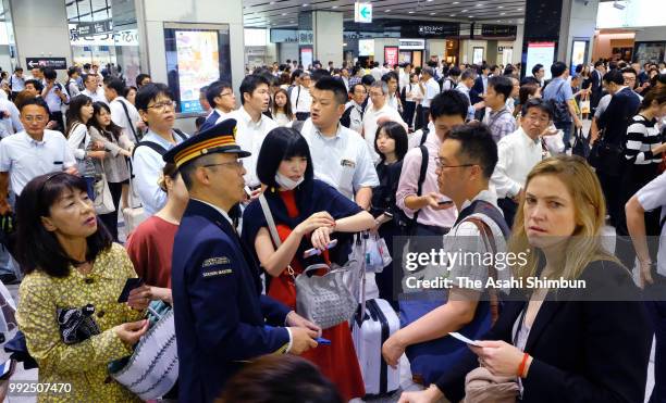 Passengers talk to a station staff as train service is partially suspended due to heavy rain at Shin Osaka Station on July 6, 2018 in Osaka, Japan....