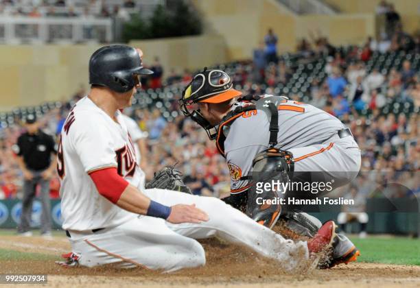 Logan Morrison of the Minnesota Twins scores a run past Chance Sisco of the Baltimore Orioles in the eighth inning of the game on July 5, 2018 at...