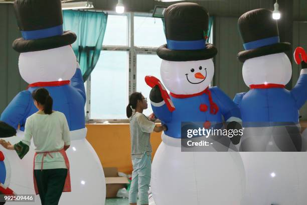 This photo taken on July 5, 2018 shows workers checking inflatable snowmen made for export at a factory in Huaibei in China's eastern Anhui province....