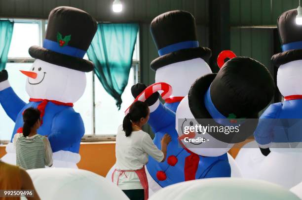 This photo taken on July 5, 2018 shows workers checking inflatable snowmen made for export at a factory in Huaibei in China's eastern Anhui province....