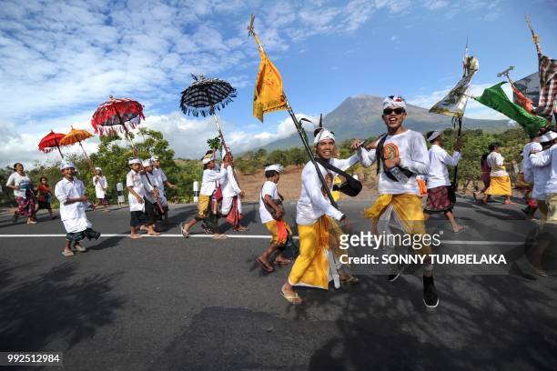 Balinese people walk before Mount Agung from Muntig village to the beach during a Melasti ceremony, a purification ceremony and ritual, in Karangasem...