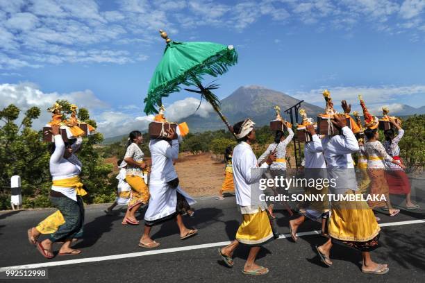 Balinese people walk before Mount Agung from Muntig village to the beach during a Melasti ceremony, a purification ceremony and ritual, in Karangasem...