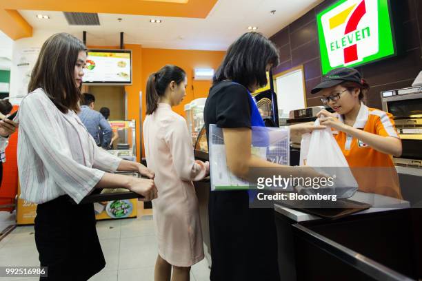An employee serves a customers at the check-out counter of a 7-Eleven store in Ho Chi Minh City, Vietnam, on Wednesday, June 20, 2018. For decades,...