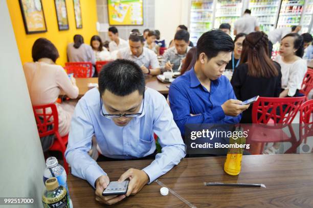 Customers sit using smartphones at a 7-Eleven store in Ho Chi Minh City, Vietnam, on Wednesday, June 20, 2018. For decades, Vietnamese have shopped,...