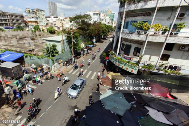 Traffic travels along a road past a market covered by parasols in Ho Chi Minh City, Vietnam, on Wednesday, June 20, 2018. For decades, Vietnamese...