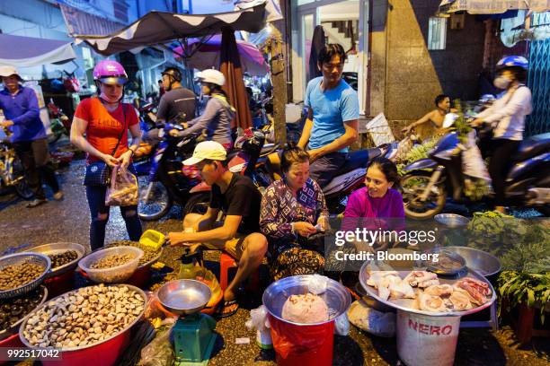 Motorcyclists pass vendors selling food in a market at night in Ho Chi Minh City, Vietnam, on Wednesday, June 20, 2018. For decades, Vietnamese have...