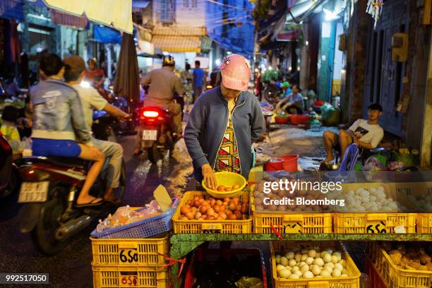 Motorcyclists pass vendors selling food in a market at night in Ho Chi Minh City, Vietnam, on Wednesday, June 20, 2018. For decades, Vietnamese have...