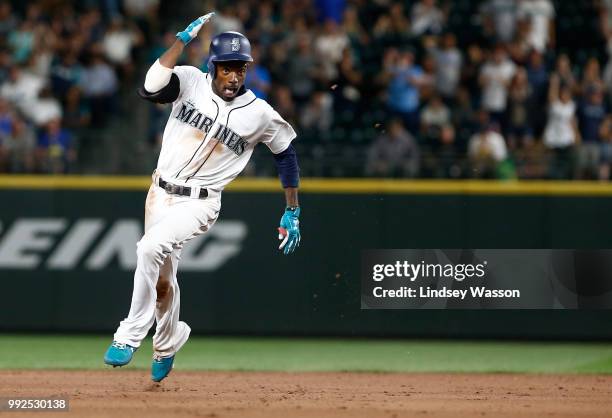 Dee Gordon of the Seattle Mariners holds on to his batting helmet as he heads for third base on a triple in the seventh inning against the Los...