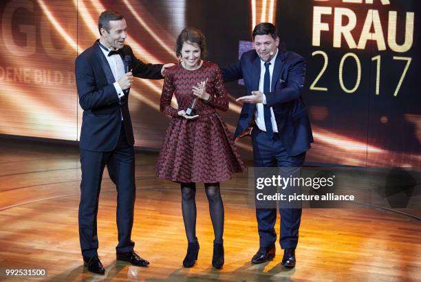 Presenter Kai Pflaume , award winner Ninon Demuth and laudator Tim Maelzer standing onstage during the the award ceremony of the "Goldene Bild der...