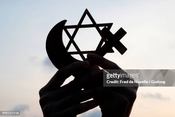 christianity, islam, judaism  3  monotheistic religions. jewish  star, cross and crescent :  interreligious symbols in hands. - cross symbol stock-fotos und bilder