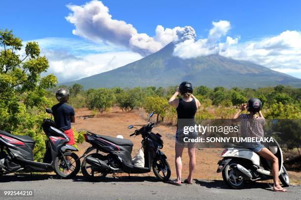 Tourists stop to take photos as Mount Agung volcano erupts again at the Kubu subdistrict in Karangasem Regency on Indonesia's resort island of Bali...