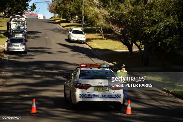 Policewoman is seen on a street where a father shot dead his teenage son and daughter at their home in Sydney on July 6, 2018. - Police said the...