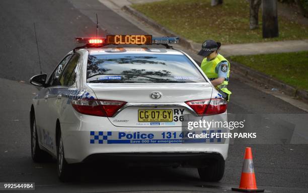 Policewoman is seen on a street where a father shot dead his teenage son and daughter at their home in Sydney on July 6, 2018. - Police said the...