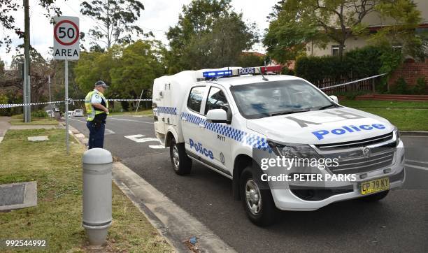 Policeman guards the entrance to a street where a father shot dead his teenage son and daughter at their home in Sydney on July 6, 2018. - Police...