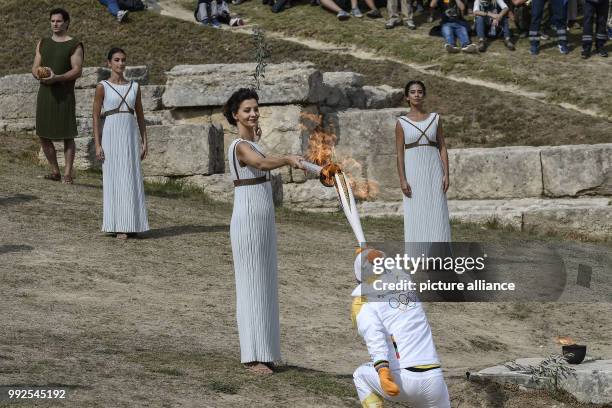 Greek actress Katerina Lehou playing the role of High Priestess, passes the flame to the first torchbearer, Greek cross country skiing athlete...