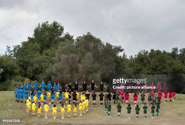 Athletes wearing different colours form the olympic symbol at a ceremonial lighting of the olympic torch in Olympia, Greece, 24 October 2017. The...