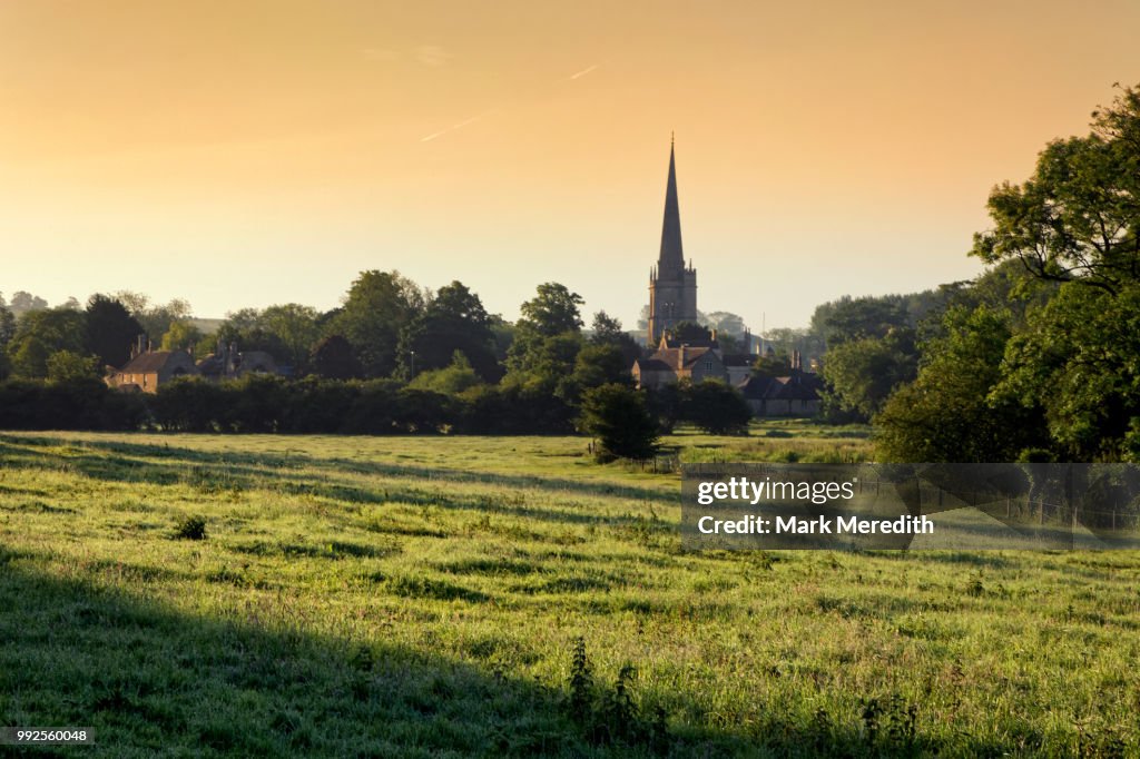 Burford church spire, by the banks of the River Windrush, sunset, in the Cotswolds