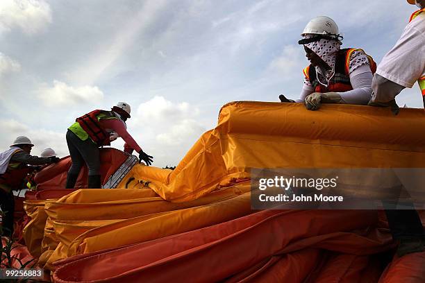 Contract workers fold oil booms to protect marshlands along the Gulf of Mexico on May 13, 2010 in Hopedale, Louisiana. The BP Deepwater Horizon oil...