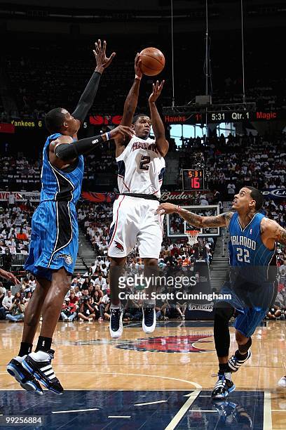 Joe Johnson of the Atlanta Hawks passes the ball over Dwight Howard and Matt Barnes of the Orlando Magic in Game Three of the Eastern Conference...