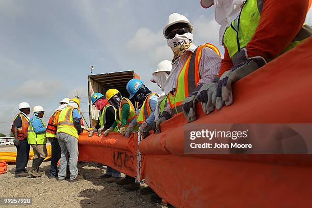 Oil spill workers connect sections of oil booms to protect marshlands in the Gulf of Mexico on May 13, 2010 in Hopedale, Louisiana. The BP Deepwater...