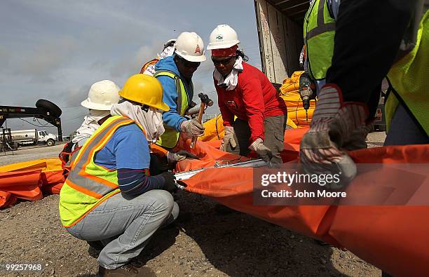 Oil spill workers connect sections of oil booms to protect marshlands in the Gulf of Mexico on May 13, 2010 in Hopedale, Louisiana. The BP Deepwater...