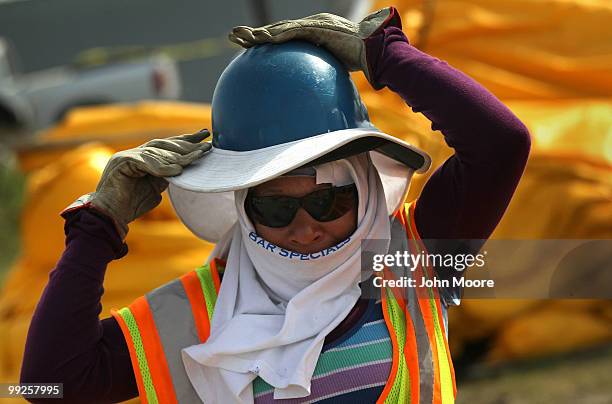 An oil spill worker adjusts her protective gear while unloading oil booms to protect marshlands in the Gulf of Mexico on May 13, 2010 in Hopedale,...