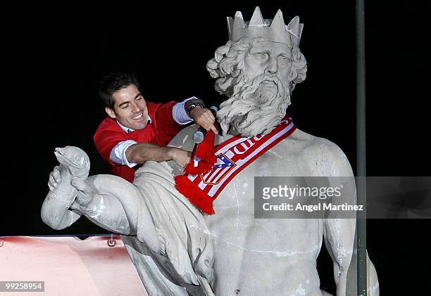 Atletico Madrid captian Antonio Lopez puts a team scarf around the neck of the Neptuno statue in Madrid the day after Atletico won the UEFA Europa...