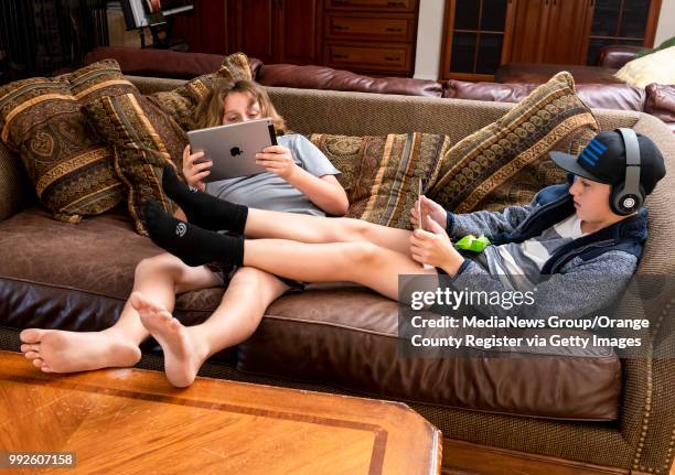 Arthur Hill left, and his brother, Conrad stay glued to their iPads as the lounge on the couch at their home in Tustin on Wednesday, June 27, 2018....