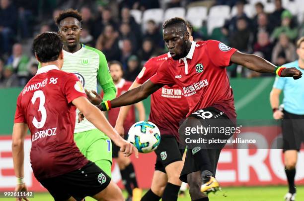 Wolfsburg's Divock Origi vying for the ball against Hannover's Miiko Albornoz and Salif Sane during the DFB Cup soccer match between VfL Wolfsburg...