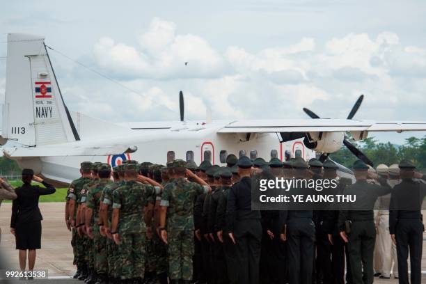 Thai soldiers and police officers pay their respects as a Thai Navy plane carrying the body of Saman Kunan, a former Thai navy diver who died on July...