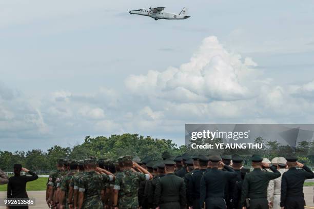 Thai soldiers and police officers pay their respects as a Thai Navy plane carrying the body of Saman Kunan, a former Thai navy diver who died on July...