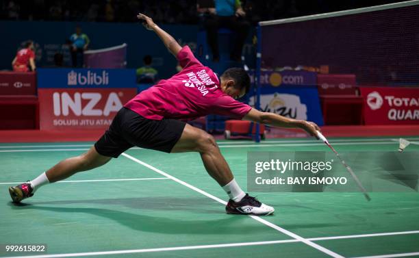 Tommy Sugiarto of Indonesia lunges for a return against Kento Momota of Japan during their men's singles quarter-final match at the Indonesia Open...