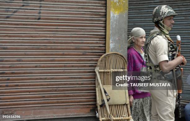 An Indian trooper stands guard as an elderly Kashmiri women looks on outside the Jamia Masjid mosque after authorities imposed restrictions in...