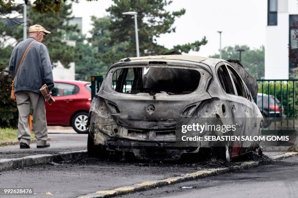Resident walks past the wreckage of a burnt-out car in the Bellevue neighborhood in Nantes on July 6 following another night of violence in the...