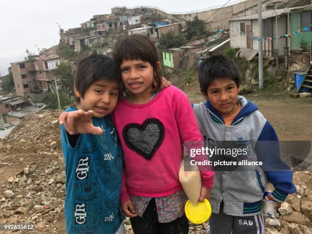 File picture showing six-year old Sajuri Rivera standing with two friends beneath the wall in the Pamplona slum in the Peruvian capital city of Lima,...