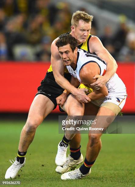 Kyle Hartigan of the Crows is tackled by Jack Riewoldt of the Tigers during the round 16 AFL match between the Richmond Tigers and the Adelaide Crows...