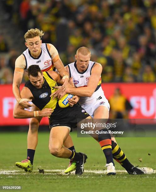 Toby Nankervis of the Tigers is tackled by Hugh Greenwood and Sam Jacobs of the Crows during the round 16 AFL match between the Richmond Tigers and...